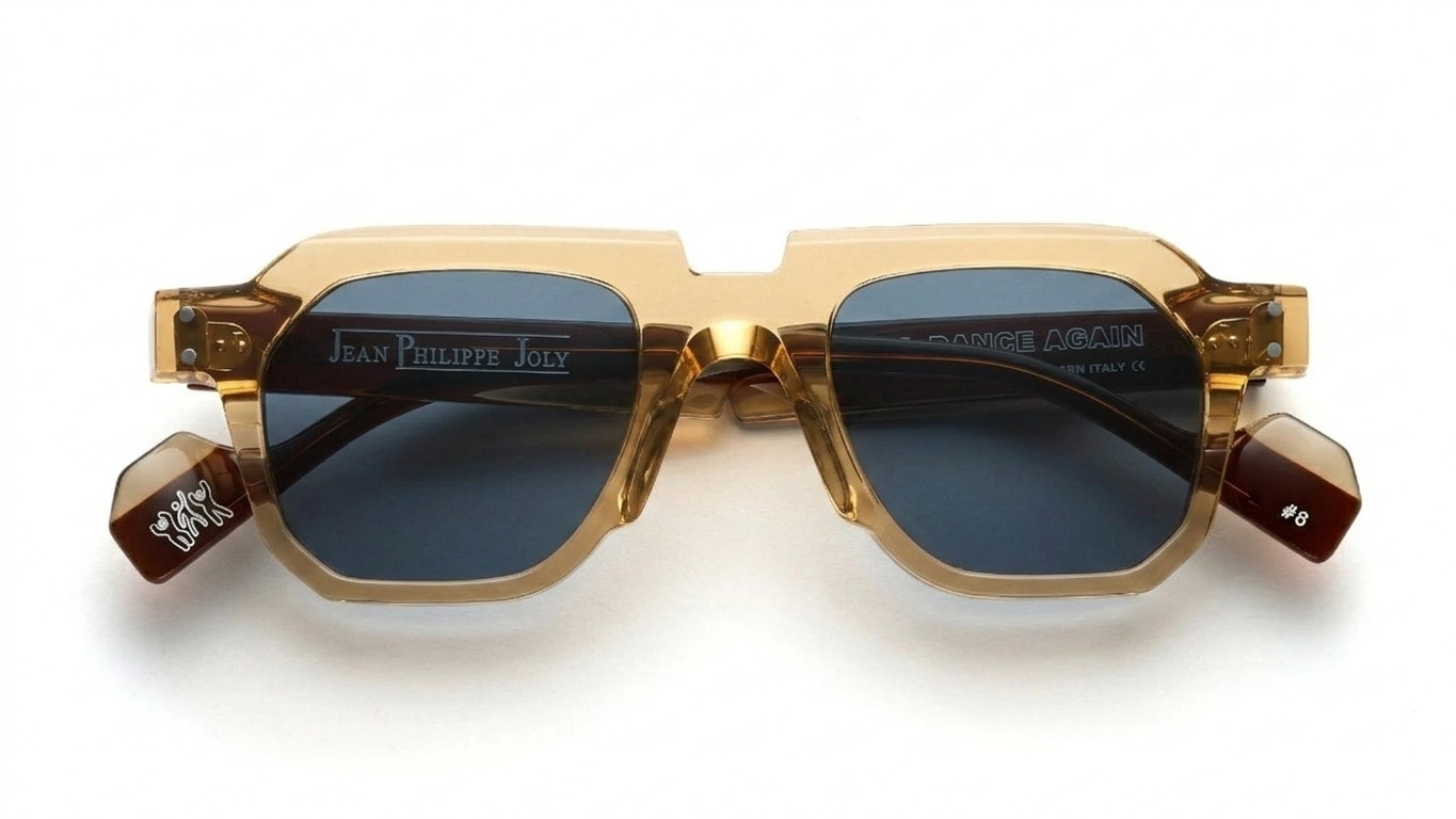 Jean Philippe Joly Dance Again sunglasses with a translucent gold acetate frame, dark blue lenses, and brown tortoiseshell temple tips, shown on a white background.