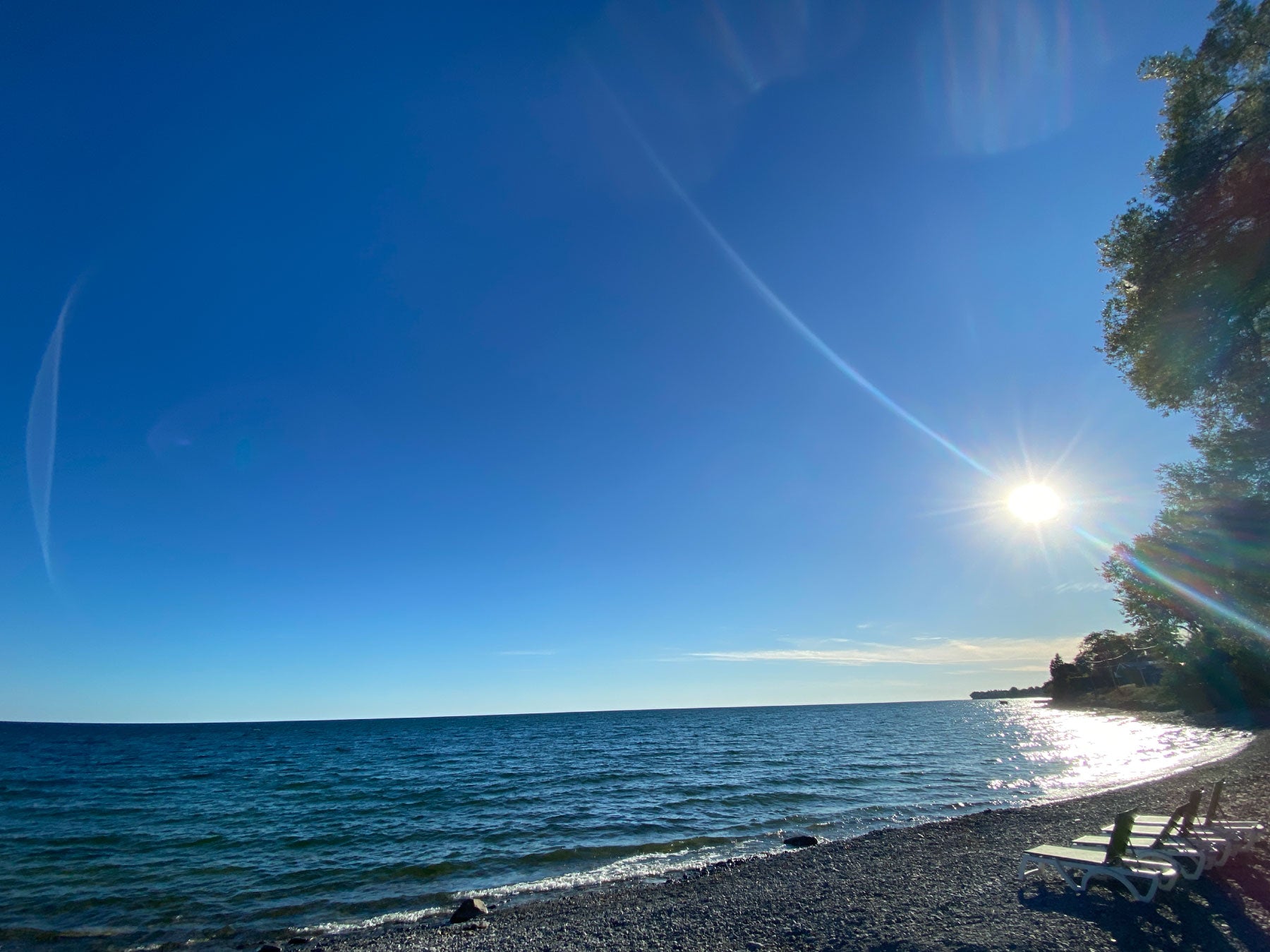 Wellington Beach scene with clear blue sky, sun, and calm water.