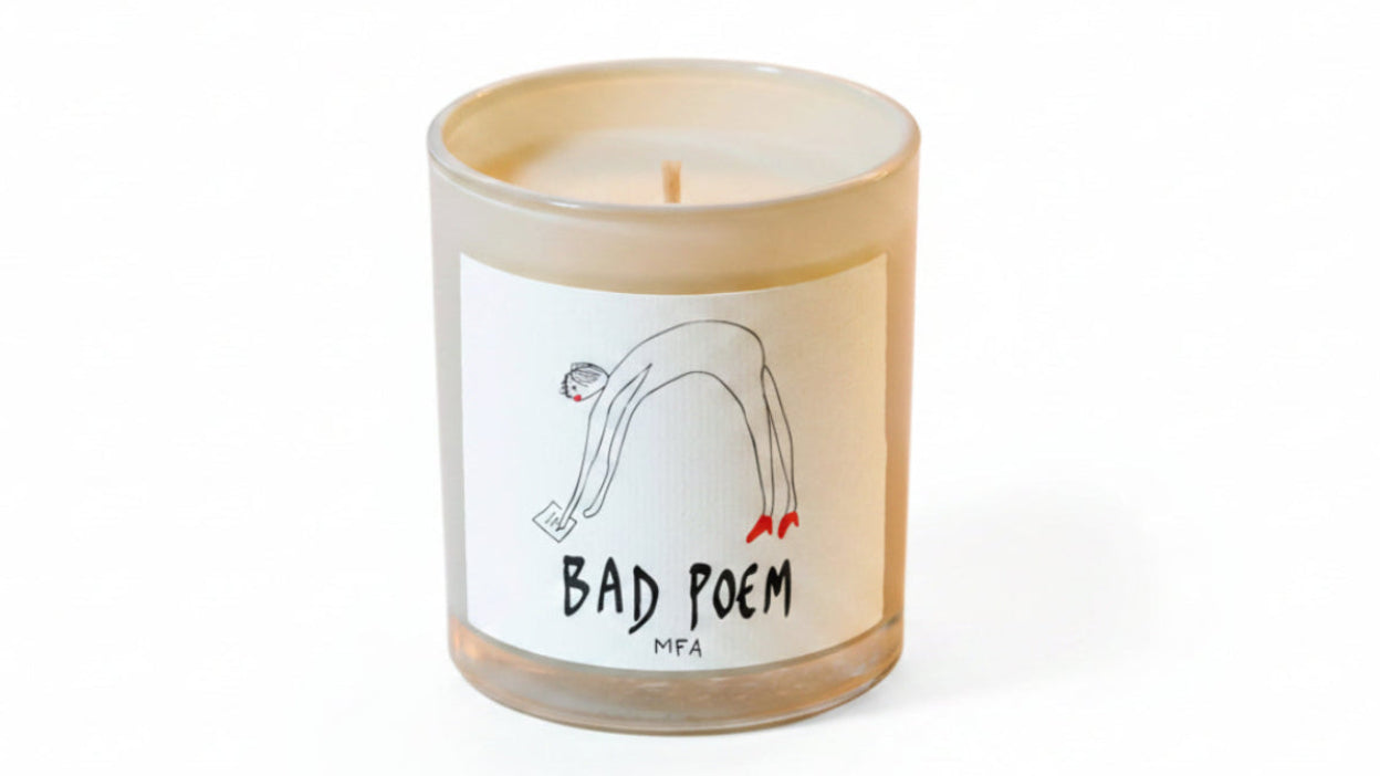 A single-wick candle in a clear glass jar with cream-colored wax and a white label. The label features a minimalist black line drawing of a person stretching with small red details and the text 'BAD POEM' and 'MFA'.